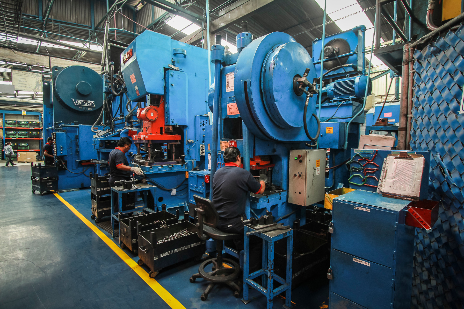 A worker in a factory uses a grinding machine, generating bright sparks in a dark industrial setting